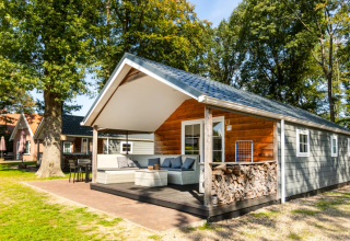 Holzchalet auf dem Campingplatz de Witte Berg in Overijssel, Niederlande, mit Terrasse und Gartenmöbeln.