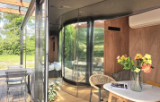 Vue intérieure et extérieure du Slowlodge Echo à Zomerlicht, Pays-Bas, avec murs en verre et déco moderne.