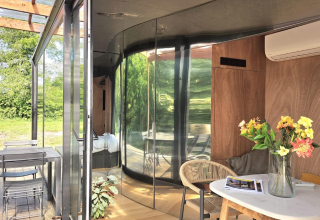 Indendørs og udendørs udsigt over Slowlodge Echo ved Zomerlicht, Holland, med glasvægge og moderne indretning.