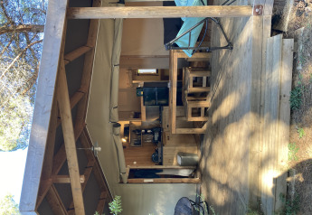 Safari tent Log cabin 'Cotton Comfort' at Flower Camping Le Bel Air, France, featuring wood deck and furniture.