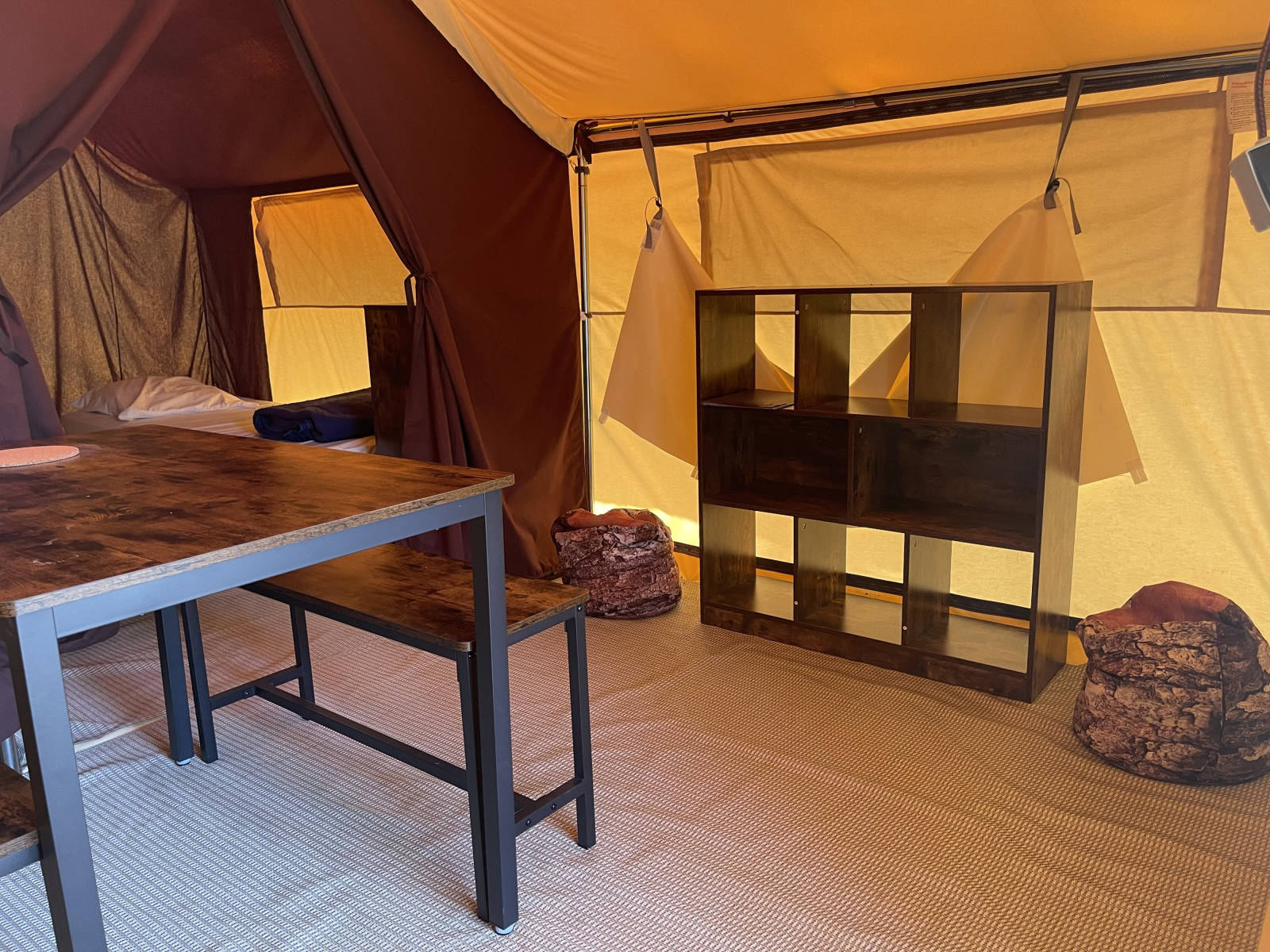 Interieur van Indiana Tent bij Camping Paradis Family des Issoux in Frankrijk met tafel, bank en kast.