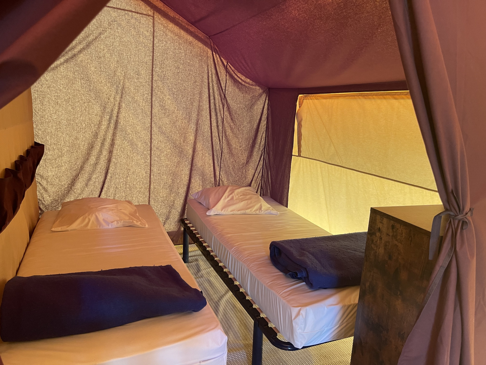 Binnenkant van Indiana Tent bij Camping Paradis Family des Issoux in Frankrijk, met twee eenpersoonsbedden.