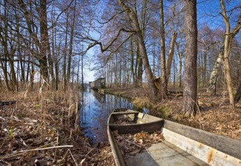 Boot aan een stille gracht tussen bomen dichtbij Bungalow «50 qm 5 Pers» in Duitsland.