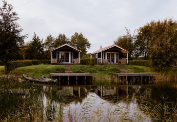 Twee charmante lodges aan een rustgevend meer, met terrassen, aanlegsteigers en omgeven door groen.