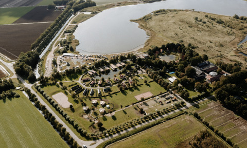 Luftaufnahme von Chalet Lodge im Holiday Park Eigen Wijze, Niederlande, neben einem großen See.