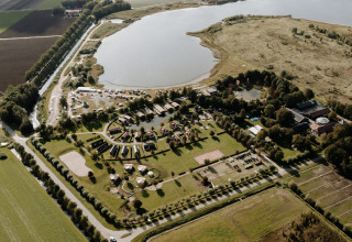 Vista aérea de Chalet Lodge en Holiday park Eigen Wijze, Países Bajos, junto a un gran lago y campos.