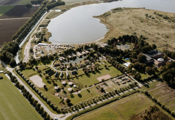 Luchtfoto van Chalet Lodge in Holiday park Eigen Wijze in Nederland vlakbij een grote vijver en velden.