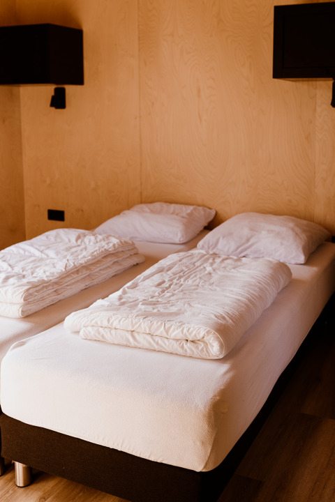 Zwei Einzelbetten mit weißer Bettwäsche im Groupaccommodation 'de Blokhut', Ferienpark, Niederlande.