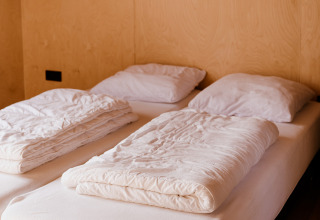 Twin beds with white bedding in Groupaccommodation 'de Blokhut' at Holiday park Eigen Wijze, Netherlands.
