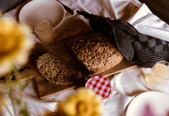 Gemütliches Frühstück mit frischem Brot, Saft und Marmelade auf einem Brett bei Glamping.