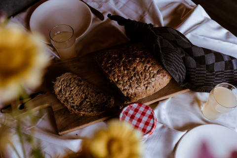 Petit-déjeuner rustique avec pain maison, jus et confiture sur une planche, ambiance glamping.