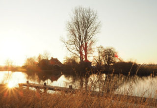 Sunset at Groupaccommodation 'de Blokhut' at Holiday park Eigen Wijze, Netherlands, beside calm water.