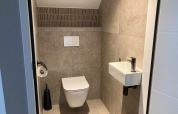 Baño moderno con inodoro suspendido y pequeño lavabo en Duinvilla de EuroParcs Texel, Países Bajos.