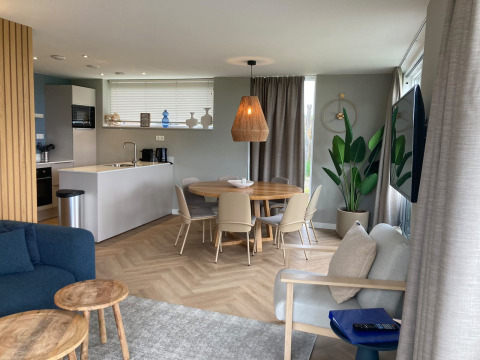 Modern lodge interior with open kitchen, dining area, and living space at Duinvilla EuroParcs Texel.