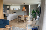 Moderne lodge med åbent køkken, spisebord og stue på Duinvilla EuroParcs Texel i Holland.