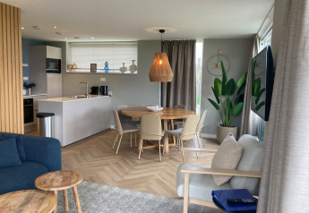 Modern lodge interior with open kitchen, dining area, and living space at Duinvilla EuroParcs Texel.