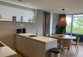 Modern kitchen and dining area at Duinvilla in EuroParcs Texel, Netherlands, with window view and bright décor.