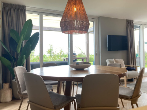 Modern lodge interior at EuroParcs Texel, Netherlands, featuring a dining table, chairs and large windows.
