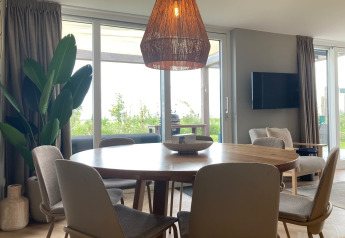 Interior de una casa rural en EuroParcs Texel, Países Bajos, con mesa de comedor y ventanales amplios.