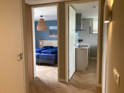 Entrance of a Duinvilla lodge at EuroParcs Texel, Netherlands, showing bedroom and kitchen interior.