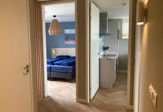 Ingang van een Duinvilla-lodge bij EuroParcs Texel, Nederland, met zicht op slaapkamer en keuken.