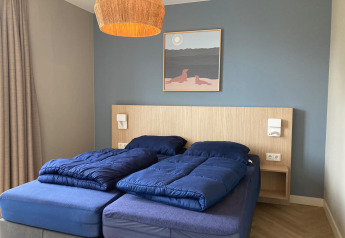 Dormitorio en Duinvilla de EuroParcs Texel, Países Bajos, con ropa de cama azul y decoración moderna.