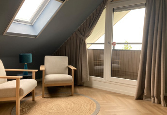 Gemütlicher Sitzbereich in einer Duinvilla bei EuroParcs Texel mit Sesseln und Dachfenster im Dachgeschoss.