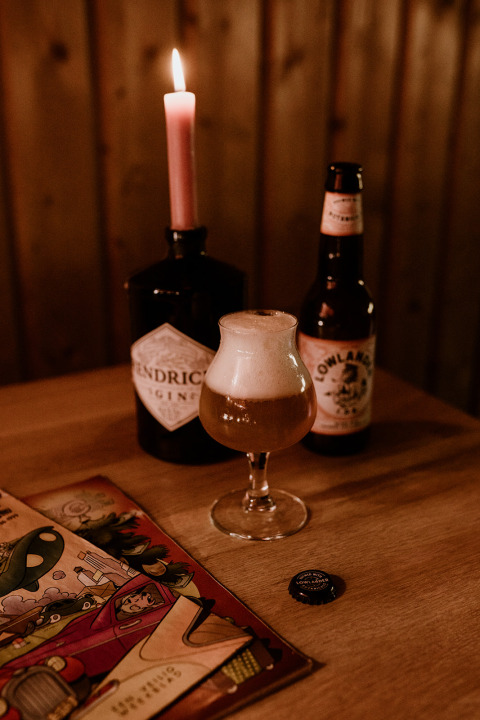 Tavolo accogliente con birra, candela accesa e fumetto al Tiny house met spiegelgevel nei Paesi Bassi.