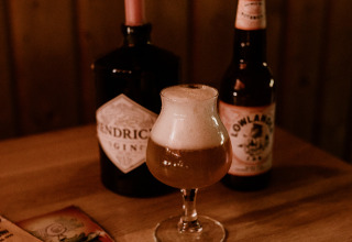 Tavolo accogliente con birra, candela accesa e fumetto al Tiny house met spiegelgevel nei Paesi Bassi.