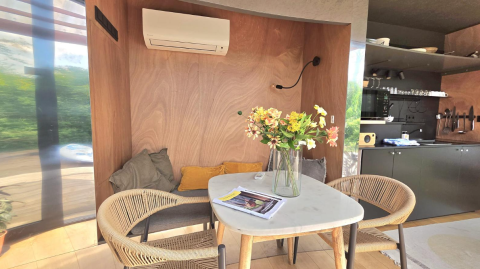 Moderne spiseplads med blomster, puder og aircondition i en lodge ved Slowlodge Echo, Zomerlicht, Holland.