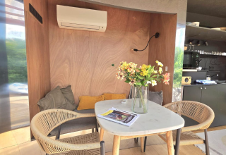 Cozy dining area with flowers, cushions, and air conditioner at Slowlodge Echo, Zomerlicht, Netherlands.