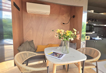 Zona pranzo accogliente con fiori, cuscini e aria condizionata a Slowlodge Echo, Zomerlicht, Paesi Bassi.