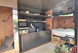Moderne lodge med åbent køkken, soveområde og naturlige træpaneler hos Slowlodge Echo, Zomerlicht, Holland.