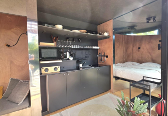 Moderne lodge med åbent køkken, soveområde og naturlige træpaneler hos Slowlodge Echo, Zomerlicht, Holland.