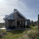 Modern lodge named Duinvilla Wellness with large windows and covered terrace in a scenic natural setting.