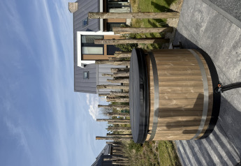Holzbadezuber mit Deckel steht vor einer modernen Lodge bei Duinvilla, EuroParcs Texel, Niederlande.