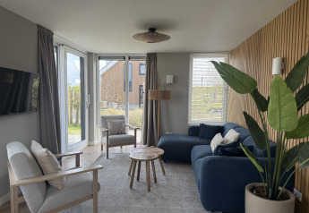 Contemporary living room at Duinvilla, EuroParcs Texel, Netherlands, with cozy seating, sunlight, and indoor plant.