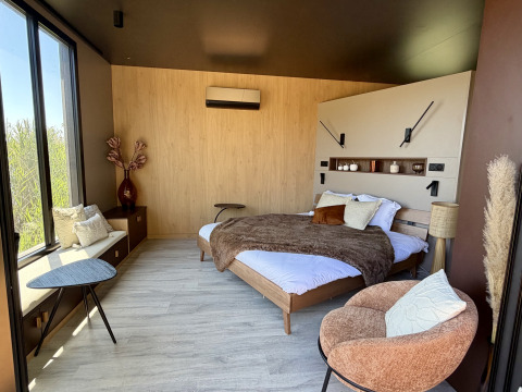 Camera moderna al Cabane Spa Loggy con letto matrimoniale, poltrona accogliente e grandi finestre.