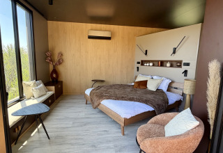 Camera moderna al Cabane Spa Loggy con letto matrimoniale, poltrona accogliente e grandi finestre.
