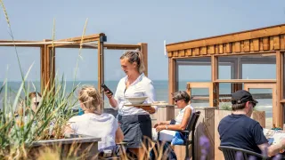 Gäste genießen das Essen im Freien auf Camping Kogerstrand mit Meerblick in Nordholland, Niederlande.