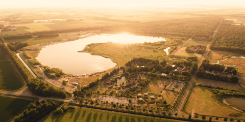 Aerial view of the Group lodge at Holiday park Eigen Wijze in the Netherlands, showing lake and fields.
