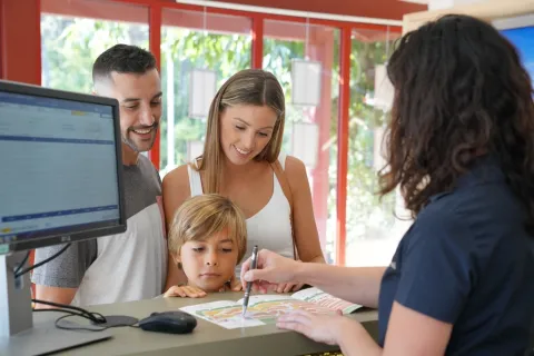 Een familie checkt in aan het onthaal van Seasonova Camping Barberousse in Occitanië, Frankrijk.