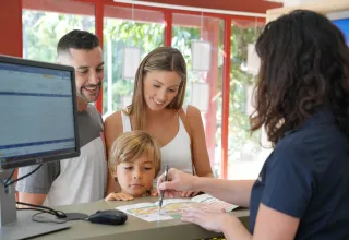 Een familie checkt in aan het onthaal van Seasonova Camping Barberousse in Occitanië, Frankrijk.