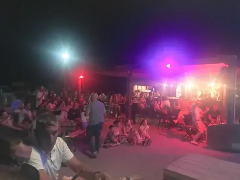Gruppe mennesker nyder en aften i fællesområdet på Seasonova Camping Barberousse, Occitanie, Frankrig.
