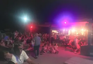 Gruppe mennesker nyder en aften i fællesområdet på Seasonova Camping Barberousse, Occitanie, Frankrig.