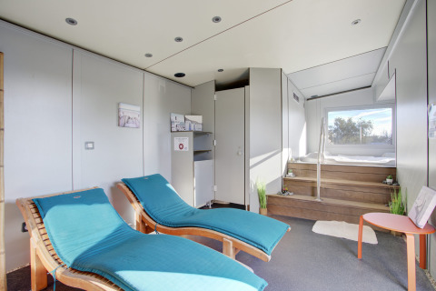 Moderne wellnessruimte met twee turquoise ligzetels, jacuzzi en groot raam in Seasonova Camping Barberousse.