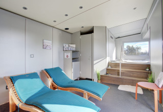 Moderne wellnessrum med to turkise liggestole, trætrin til boblebad og stort vindue på Seasonova Camping Barberousse.