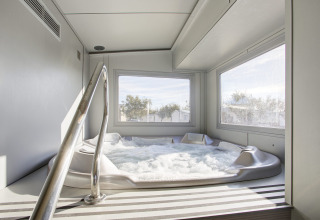Indendørs boblebad med store vinduer og udsigt over træer på Seasonova Camping Barberousse i Occitanie, Frankrig.