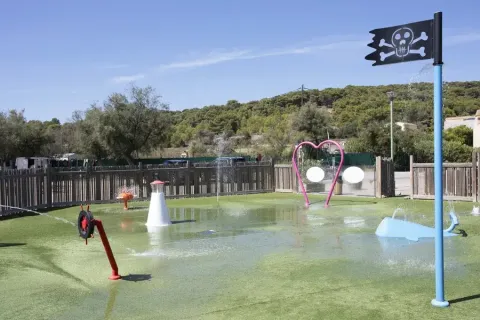 Vandlegeplads med piratflag, farverige legeredskaber og hjerteformet bue i Seasonova Camping Barberousse.