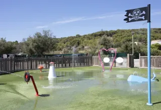 Vandlegeplads med piratflag, farverige legeredskaber og hjerteformet bue i Seasonova Camping Barberousse.
